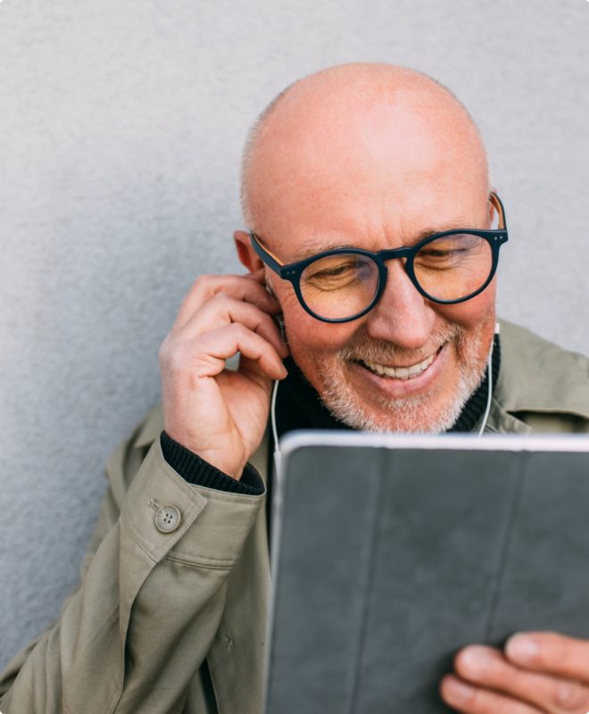 Man with earphones smiling and looking at an ipad